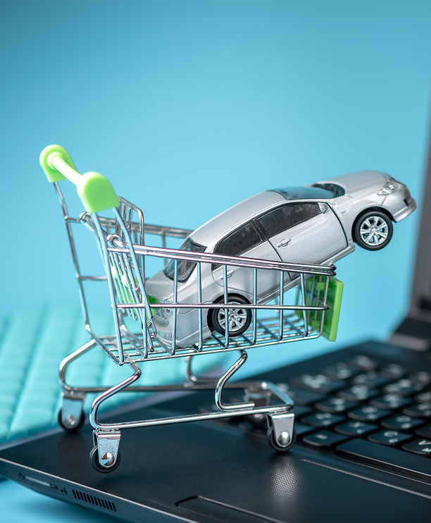 Model of a mini shopping basket with a car on a laptop keyboard.